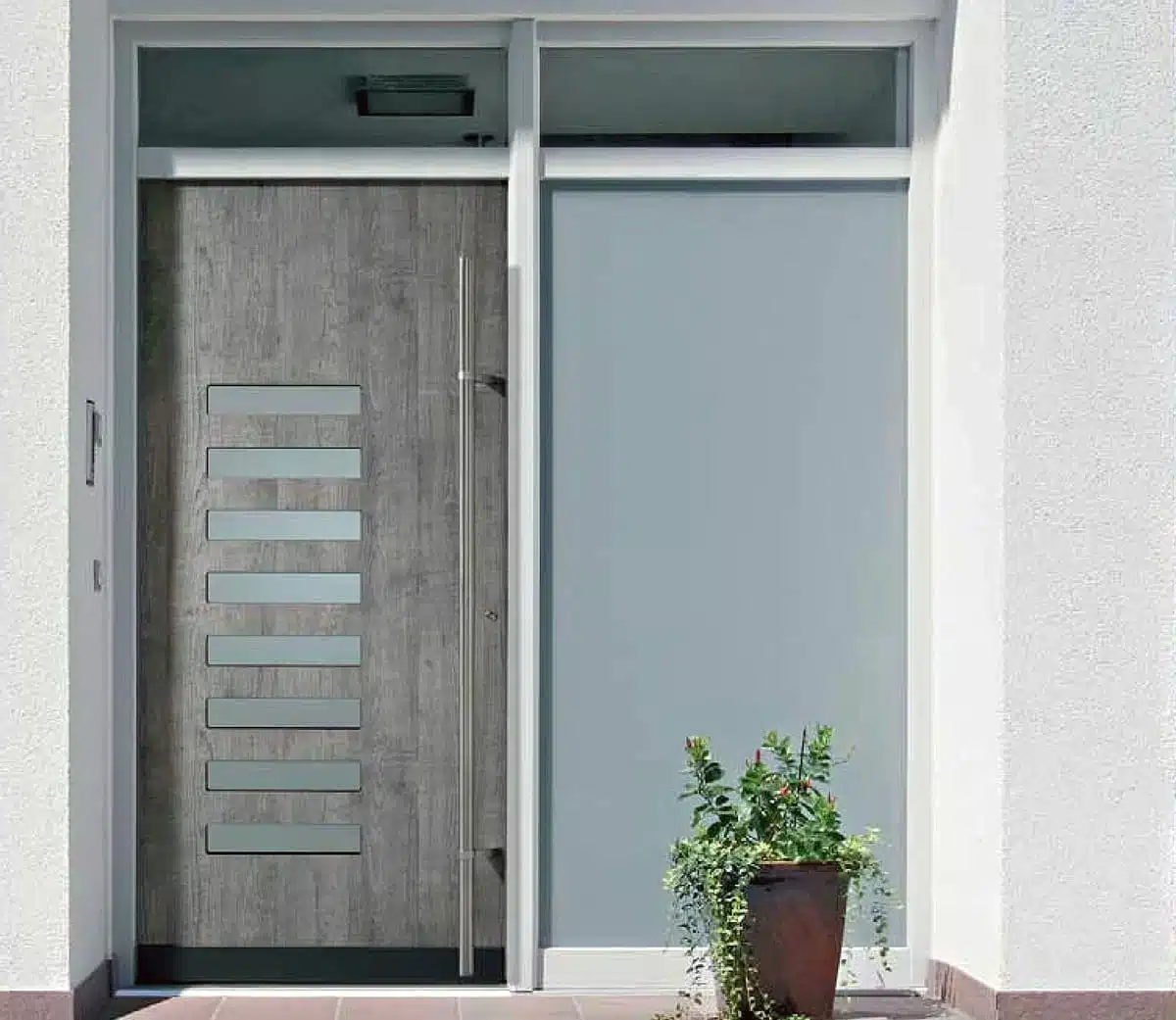 Porte d’entrée Finstral en aluminium et céramique, au design contemporain avec inserts vitrés horizontaux et poignée bâton maréchal inox. Alliance de robustesse, d’esthétique et de haute isolation thermique.